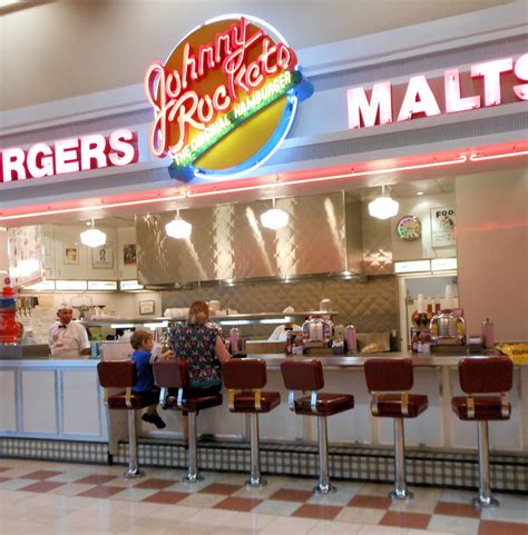 Johnny rockets restaurant - The Johnny Rockets themed decor is based upon 1950s diner-style restaurants. Décor includes Coca-Cola advertising, featuring nearly life-size cardboard illustrations of women in World War II armed services uniforms, individual jukebox stations, chrome accents and red vinyl seats.